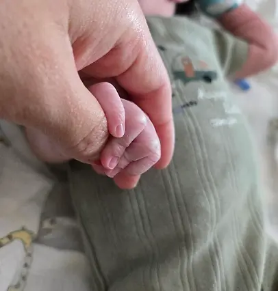 Neonatal baby holding parents hand