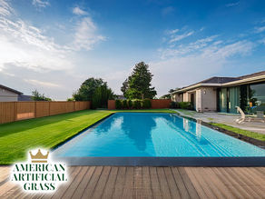 beautiful swimming pool in back of modern residential home surrounded by pavers and synthetic turf artificial grass landscaping