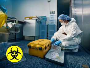 interior crime trauma scene with a technician wearing PPE, gently placing equipment into a sealed container