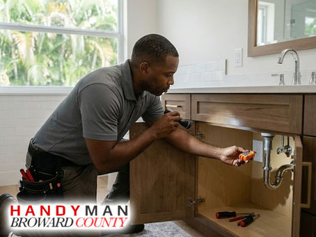 Technician inspecting a bathroom sink plumbing pipe and checking a nearby electrical outlet in a Broward County home