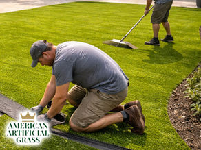 Installation crew laying down artificial grass in a Boca Raton backyard, leveling base and trimming edges for a perfect fit