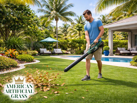 A homeowner blowing leaves artificial turf maintenance in a Boca Raton backyard, with bright green grass, palm trees, and clean landscaping