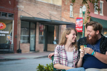 Couple sitting on bench eating ice cream.