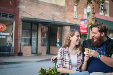 Couple sitting on bench eating ice cream.