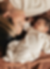New mother lovingly looking at her sleeping infant on a warm blanket.