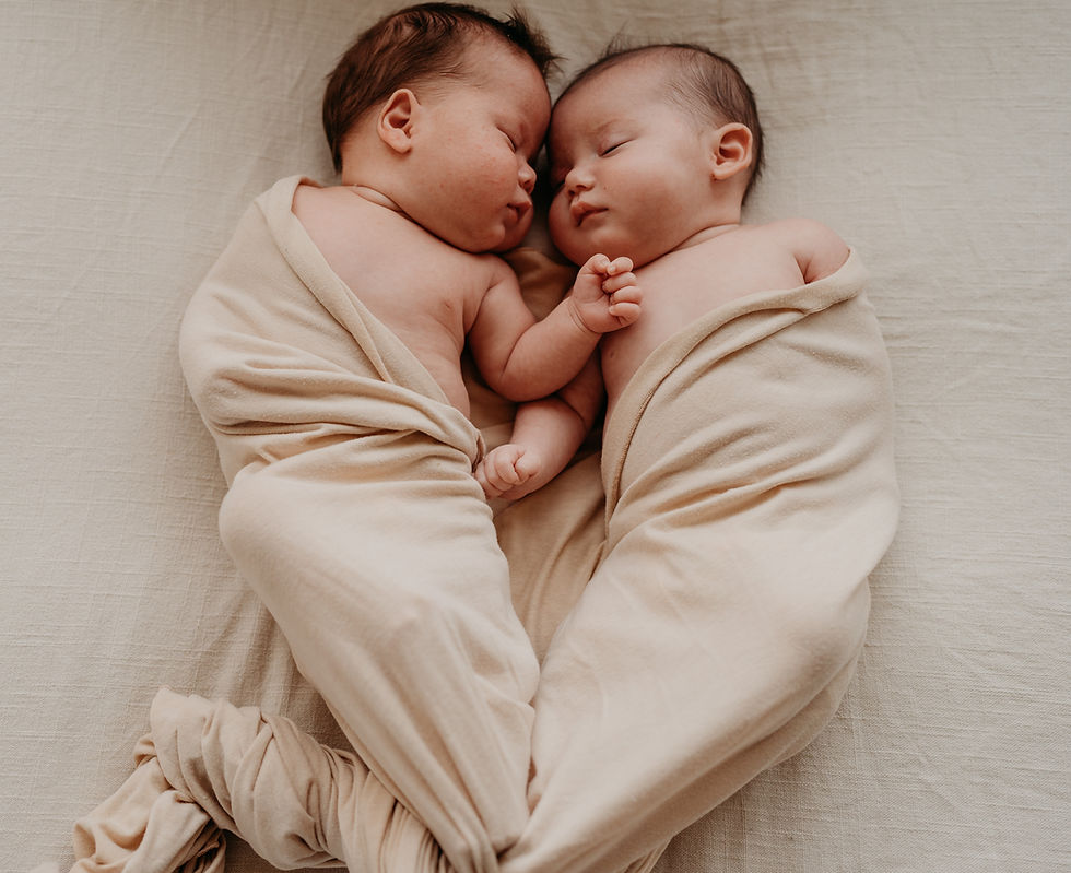 Adorable newborn twins sleeping soundly, wrapped in soft, light blankets.