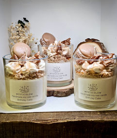 MysticGlow handmade soy wax candles with Birthday Cake scent, topped with realistic macaron, caramel drizzle, and whipped wax frosting – dessert-style artisan candles in glass jars.