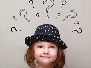 Petite fille souriante portant un chapeau noir à étoiles, entourée de points d’interrogation sur fond beige.