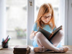 Une petite fille placé les jambes croisés lisant un livre