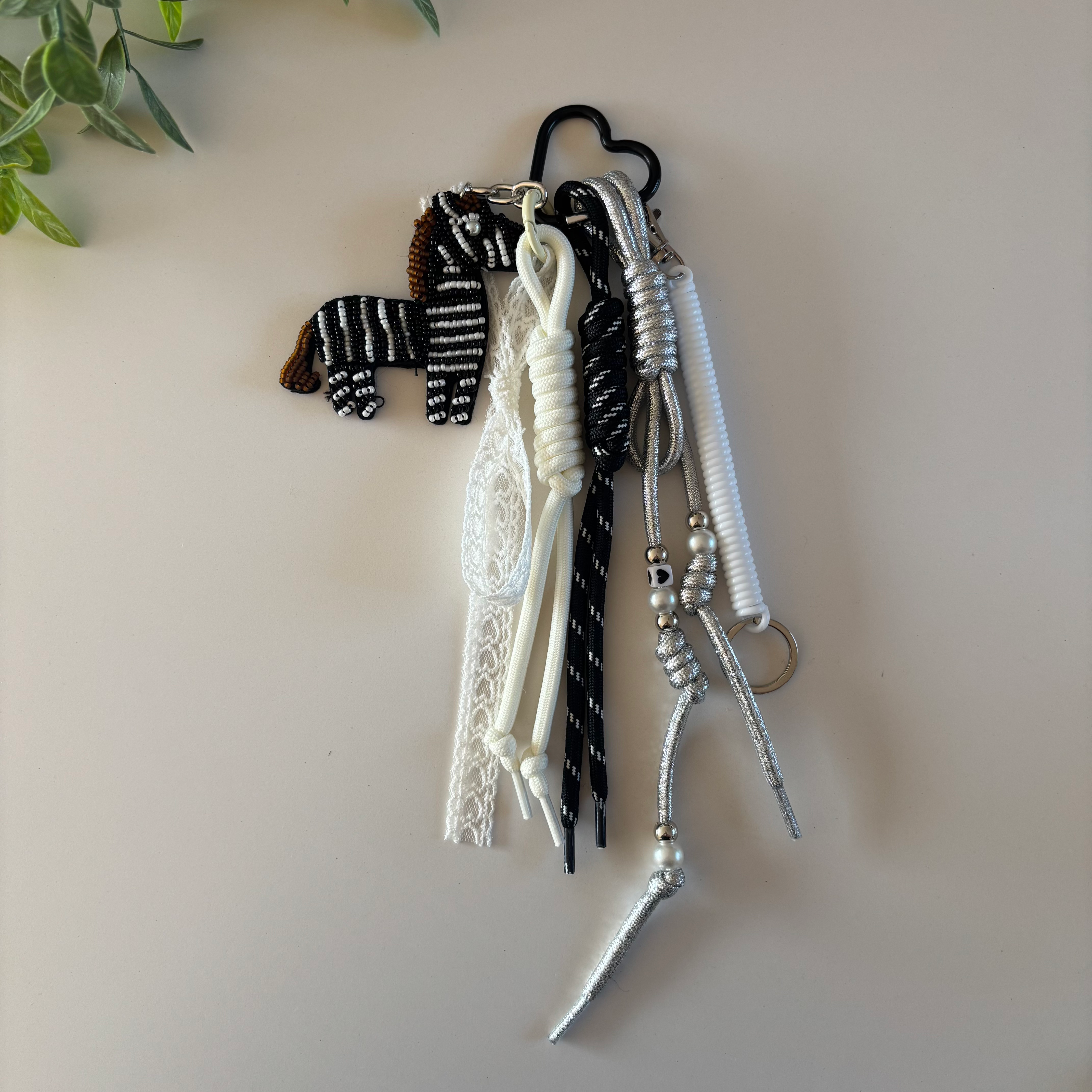 Porte-clés bijou de sac zèbre noir et blanc avec dentelle blanche, cordons et détails argentés, anneau cœur