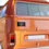 Thumbnail: A black bumper sticker that says "Impeach Elon" on the back of an orange van