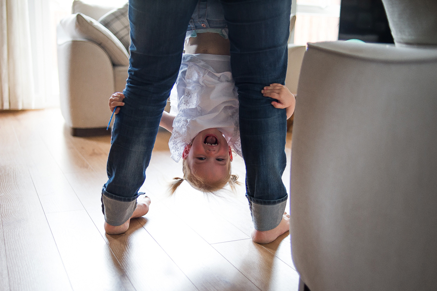Little girl hanging upside down on mum's legs - Family Photography Session at home in Dublin by Camila Lee Family Photographer 