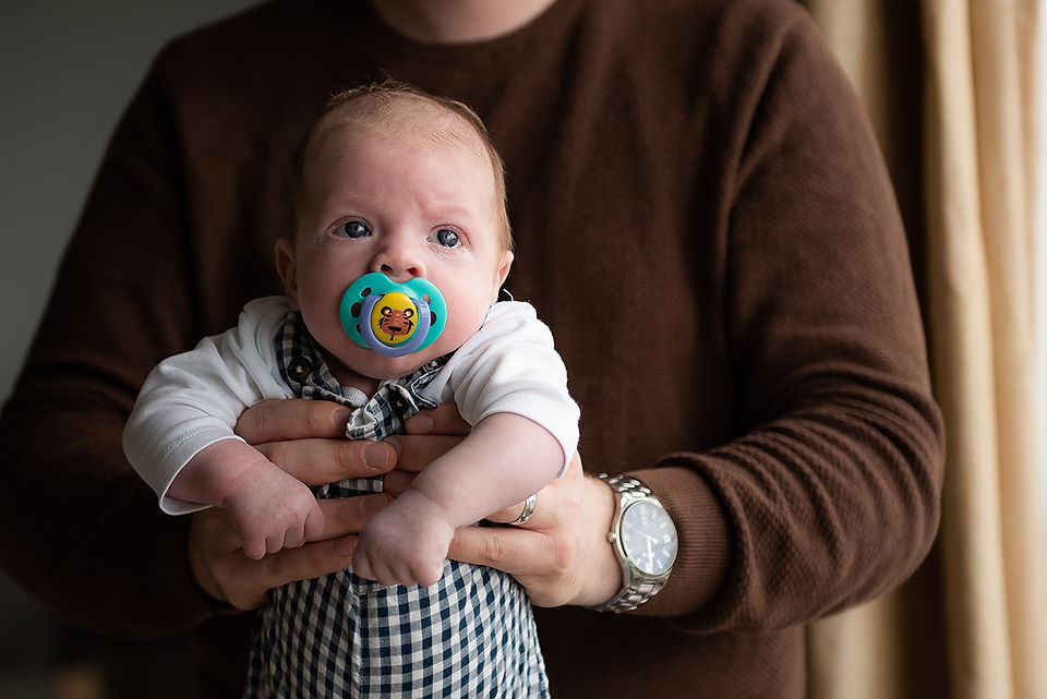 Dad holding newborn baby with a soother