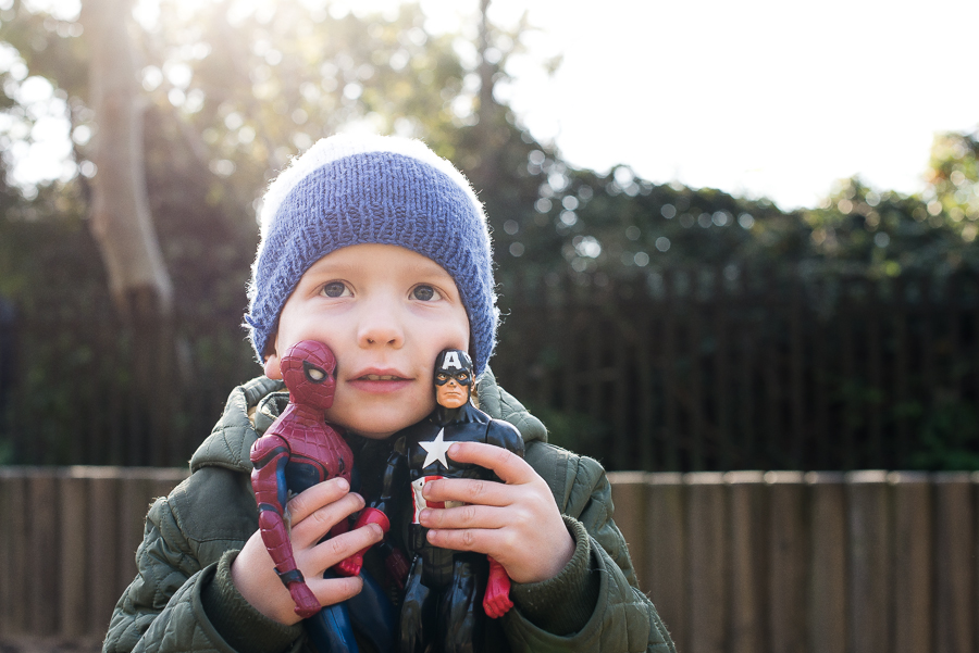 Little boy holding Captain America and Spiderman toys at the playground at Malahide Castle in Dublin