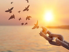 AI generated picture of a chain turning into birds in front of a sunny sea.