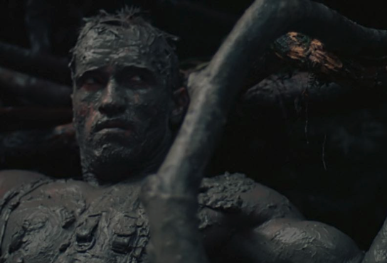 Arnold Schwarzenegger acting in the movie "Predator" camouflaged in mud 