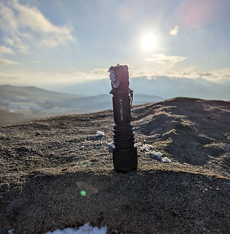 Helios torch stands on a snow covered rock as the sun rises behind it