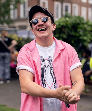 Man wearing sunglasses and a pink shirt smiling