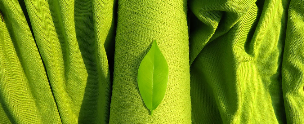GreenSustainable Fashion_ Leaf on a green yarn cone with a backdrop of a green fabric, sy
