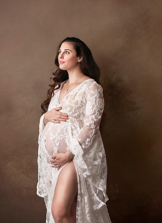 studio maternity image of woman in gorgeous white dress