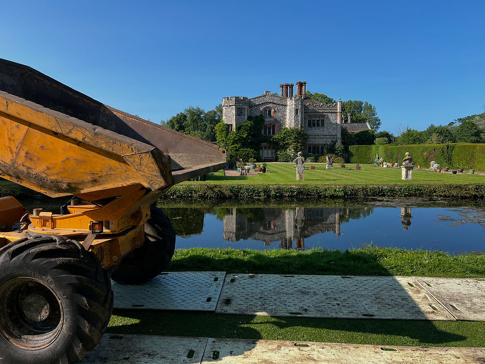 Dumper truck by water, transporting materials near a manor house