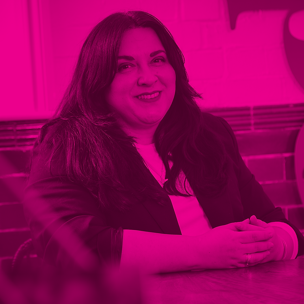 Emma Pearson-Kendall, MD of Fred Marketing sits in front of a tiled wall, wearing a dark jacket. Image is tinted pink, creating a warm, cheerful mood.