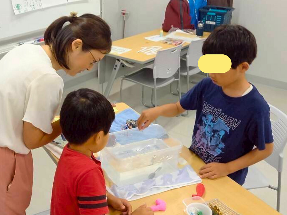 水槽にビー玉を入れる子どもとそれを見守る子供と女性