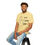 Thumbnail: T-shirt with a line drawing odd a relaxed looking child stimming by listening to music, using a tangle fidget, and moving. The shirt has text that says "Let Kids Stim" | color: butter