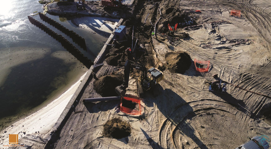 Construction site with heavy machinery, sand, and water. A view from above.