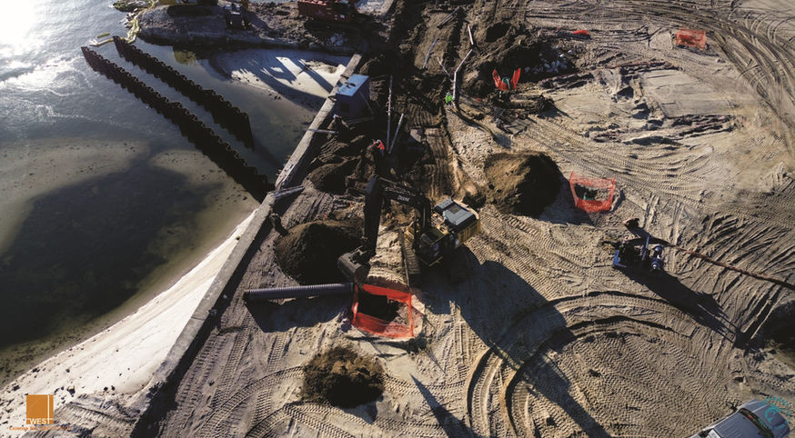 Construction site with heavy machinery, sand, and water. A view from above.