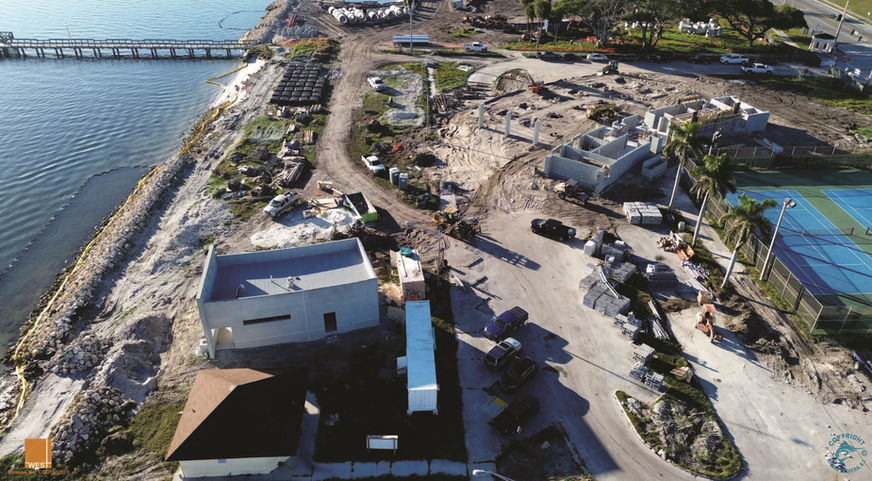 Aerial view of a construction site with buildings, bridge, and road.