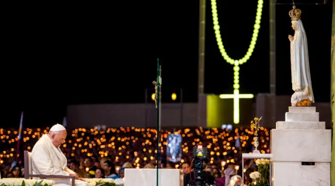 Velas com intenção durante o rosário em Fátima, representando pedido para rezar o terço no Santuário