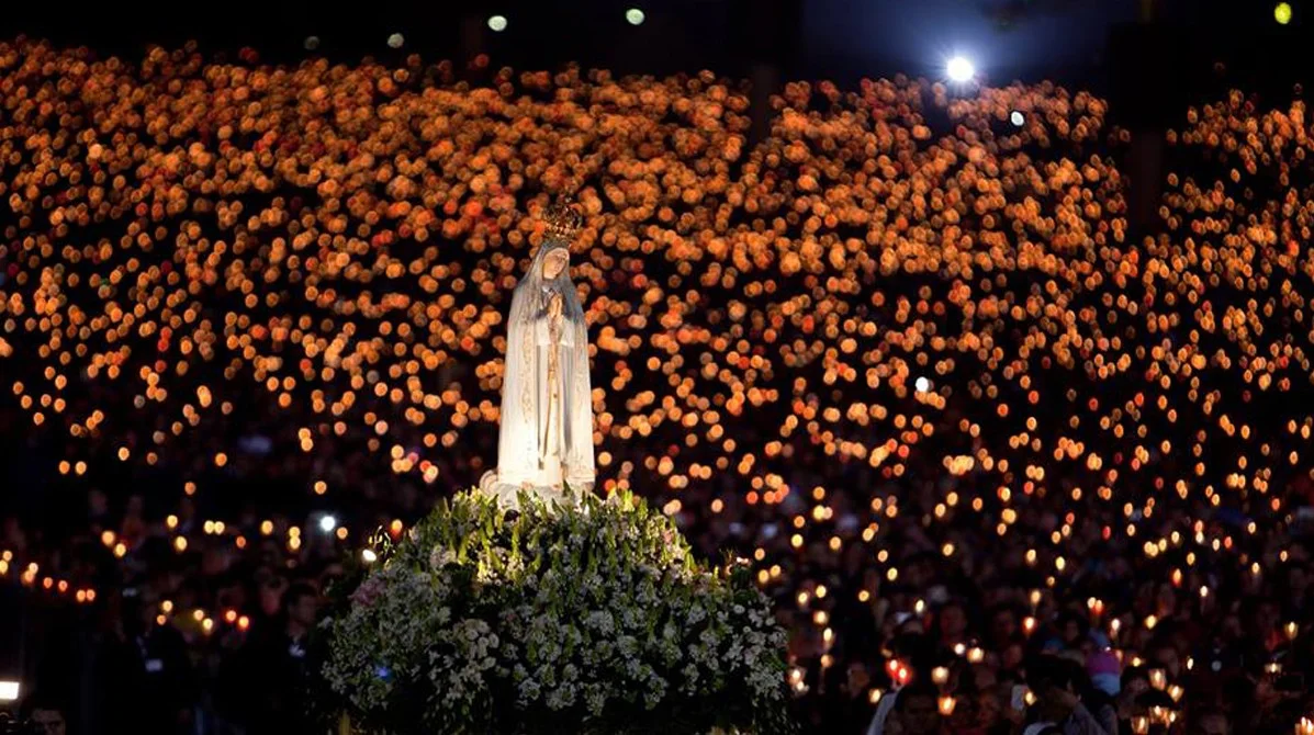 Statue of Our Lady of Fatima surrounded by candles during a prayer gathering, symbolizing peace, devotion, and spiritual grace