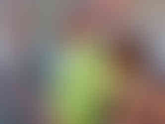 Cristian sonriente con la protagonista en bikini verde frente a una pared urbana.