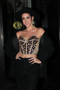  Shelina Sánchez posa sonriente con corsé animal print y falda negra sobre fondo negro.