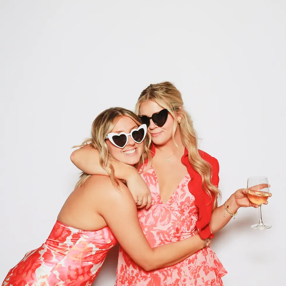 Friends in heart sunglasses and pink outfits at a summer party photo booth in Coeur d'Alene Idaho
