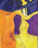 Folded orange, yellow, and purple fabrics underneath a University of Michigan baseball cap.