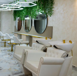 Luxe beauty salon interior with white chairs and green decor