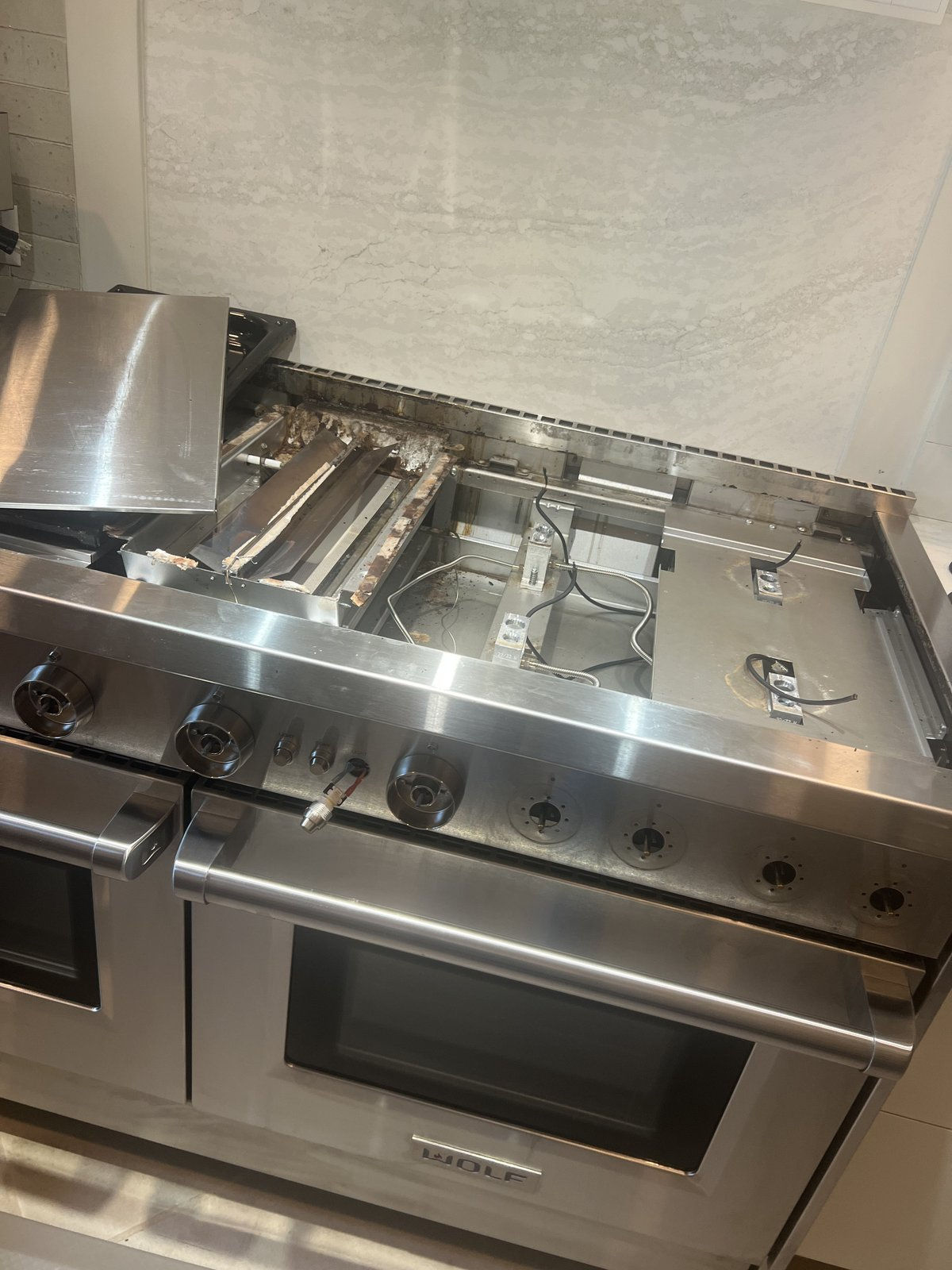Wolf range during appliance repair, with the burner area open for service