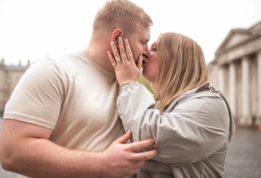 couple kissing in trinity college dublin with historic buildings in the background