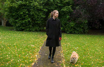 woman walking down a park pathway with her dog on a lead