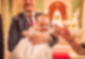 dad holding baby and she grips hand of another family member, close up detail of christening dress
