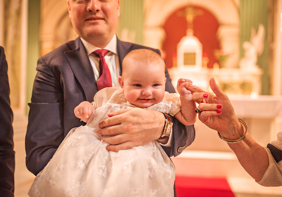 close up of hand holding baby's in her Christening gown by the alter of the church