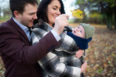 close up of mum and dad looking at baby and showing him a leaf in a Dublin park