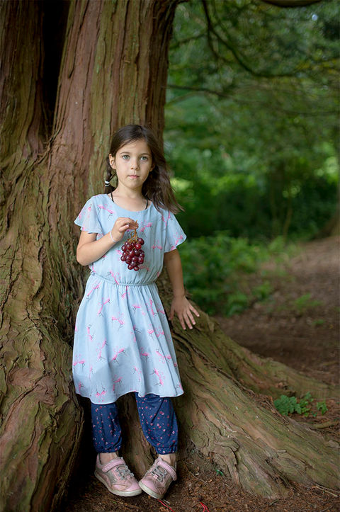 Girl holding a bunch of grapes in a forest of trees