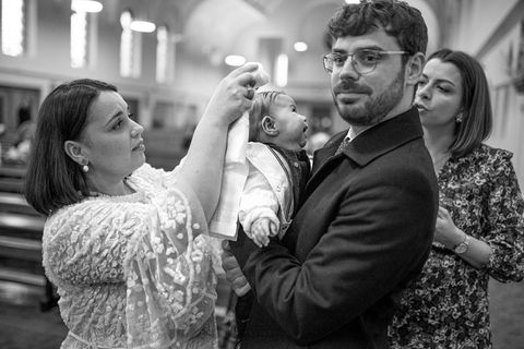 mum dressing baby in church in baptism gown with a cross