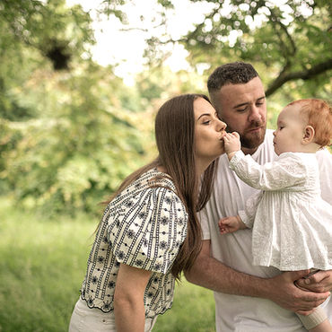 mum and dad with baby girl under tree during spring time in a Dublin park