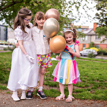 Communion girl with friends and family playing with balloons in the park on a sunny day