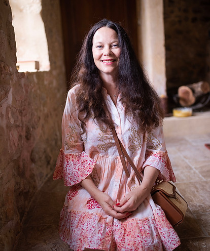 caroline mcelwee, astrologer and reiki master in pink dress and holding straw bag