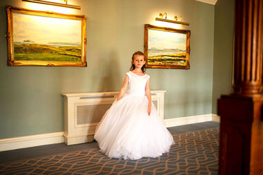girl in a communion gown in hotel with paintings in background